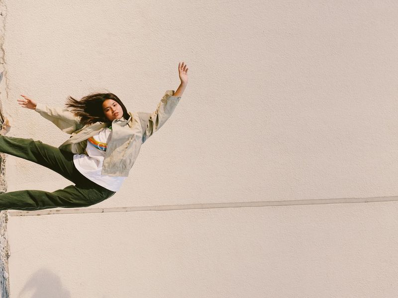 Person in a dynamic stretching pose against a dark background.